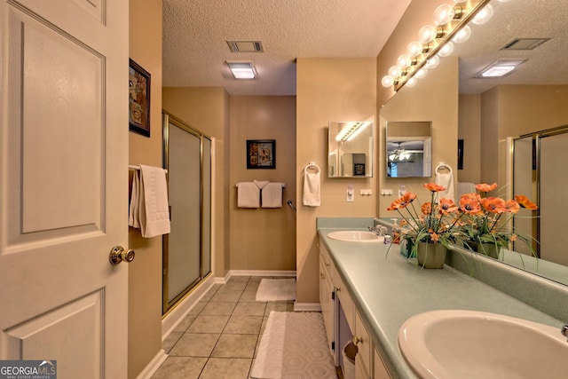 bathroom featuring tile patterned flooring, vanity, an enclosed shower, and a textured ceiling