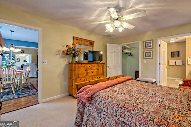 carpeted bedroom with ceiling fan with notable chandelier and a textured ceiling