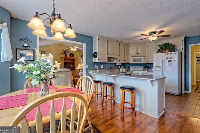 kitchen featuring hanging light fixtures, kitchen peninsula, hardwood / wood-style flooring, white appliances, and white cabinets