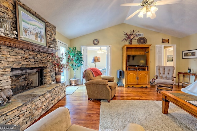 living room featuring ceiling fan, lofted ceiling, hardwood / wood-style floors, and a fireplace