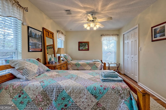 bedroom featuring ceiling fan, wood-type flooring, a closet, and a textured ceiling