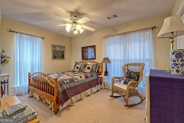 carpeted bedroom with multiple windows, ceiling fan, and a textured ceiling