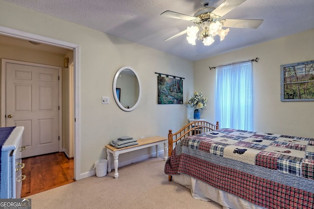 carpeted bedroom with ceiling fan and a textured ceiling