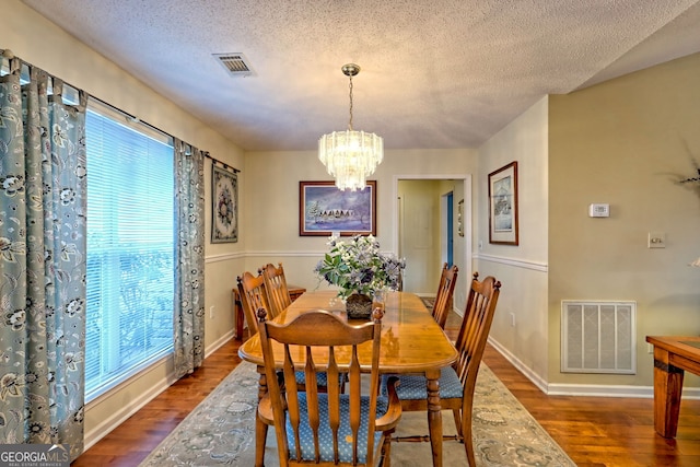 dining room with dark hardwood / wood-style flooring, a textured ceiling, and a notable chandelier