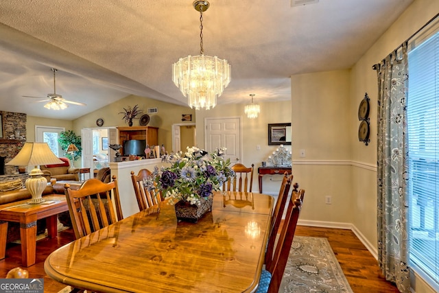 dining space with hardwood / wood-style flooring, lofted ceiling, ceiling fan with notable chandelier, and a textured ceiling