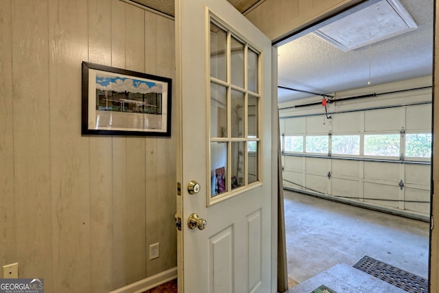 doorway with wooden walls, concrete flooring, and a textured ceiling