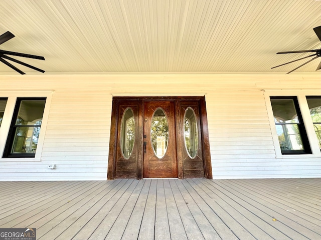 view of exterior entry featuring a deck and ceiling fan