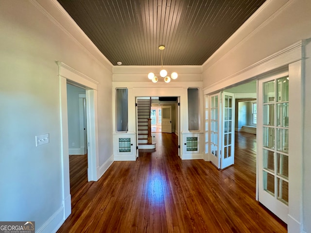 unfurnished dining area featuring french doors, dark wood-type flooring, wooden ceiling, ornamental molding, and a chandelier