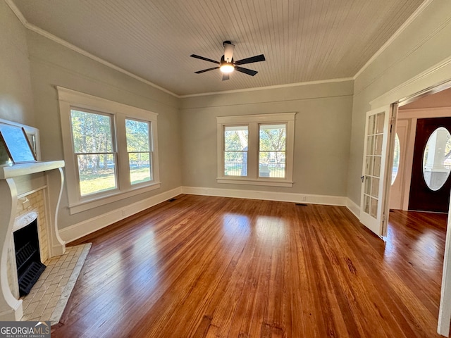 unfurnished living room with ornamental molding, wood-type flooring, a tile fireplace, and ceiling fan