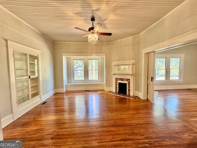 unfurnished living room with a healthy amount of sunlight, built in features, and hardwood / wood-style floors