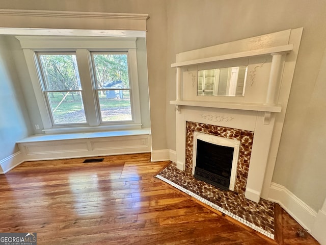 interior space with a tiled fireplace and wood-type flooring