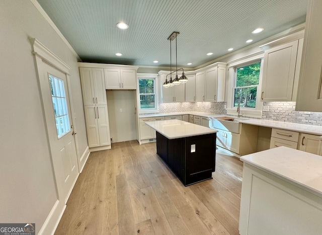 kitchen with a wealth of natural light, sink, a center island, decorative light fixtures, and light hardwood / wood-style floors