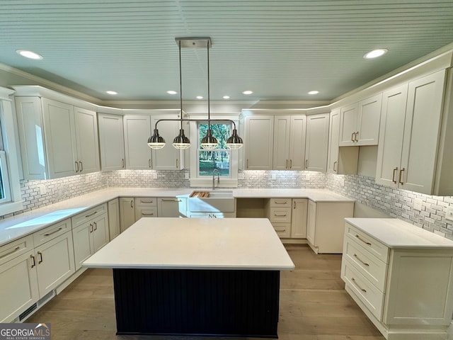 kitchen featuring sink, a center island, hardwood / wood-style flooring, and decorative light fixtures