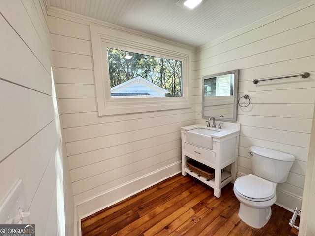 bathroom with vanity, toilet, wood-type flooring, and wooden walls