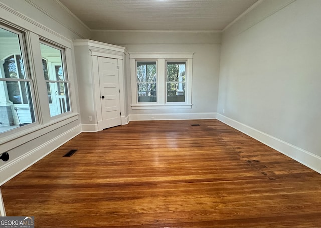 spare room featuring wood-type flooring and ornamental molding