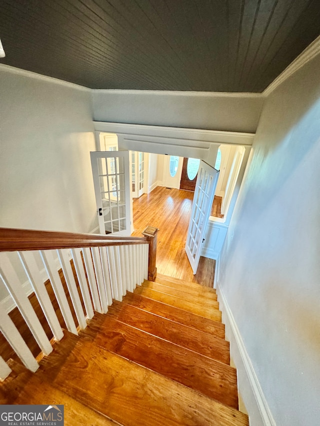 stairs with hardwood / wood-style floors and crown molding