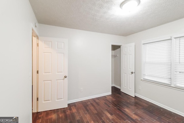 unfurnished bedroom featuring dark wood-type flooring, a textured ceiling, and a closet