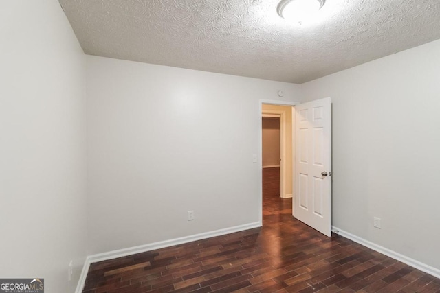 empty room with a textured ceiling and dark hardwood / wood-style flooring