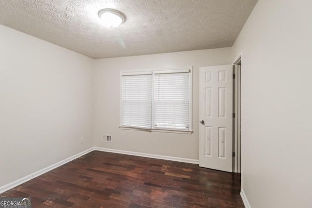 empty room featuring dark wood-type flooring and a textured ceiling