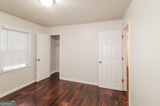 unfurnished bedroom featuring a closet, dark hardwood / wood-style floors, and a textured ceiling