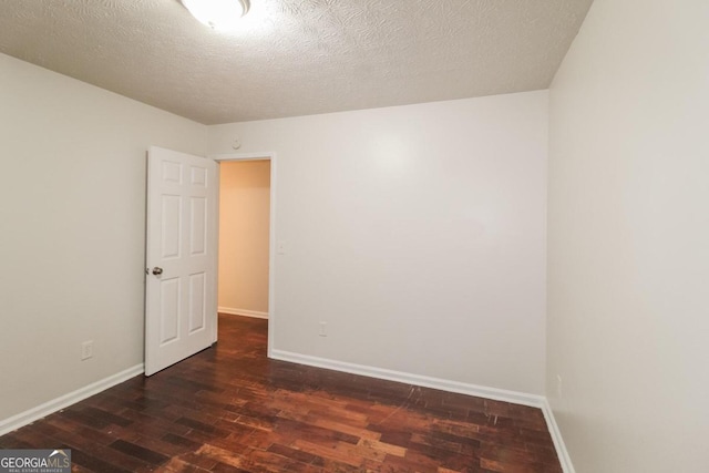 spare room with a textured ceiling and dark hardwood / wood-style flooring