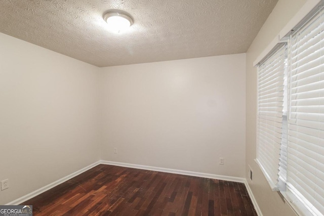 empty room with a textured ceiling and dark wood-type flooring