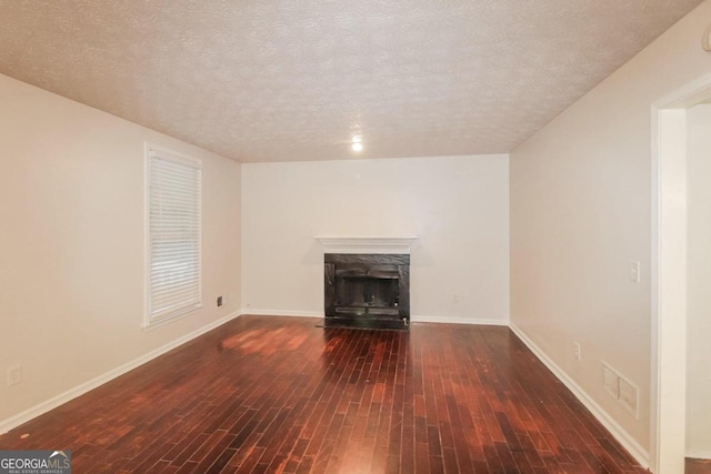 unfurnished living room with a textured ceiling and dark hardwood / wood-style floors