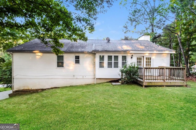 rear view of house featuring a wooden deck and a yard