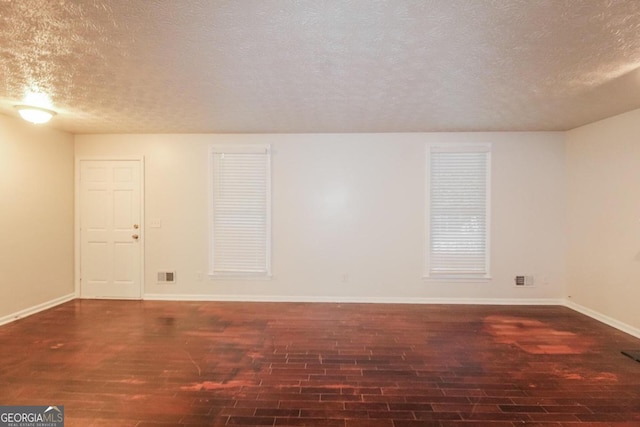 spare room with a textured ceiling and dark hardwood / wood-style floors