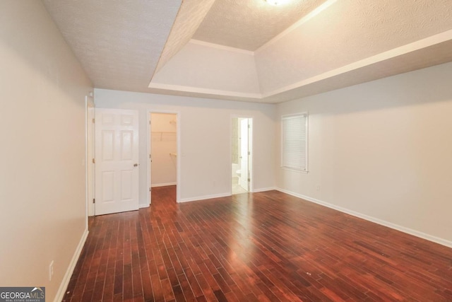 unfurnished room with a raised ceiling, a textured ceiling, and dark hardwood / wood-style floors