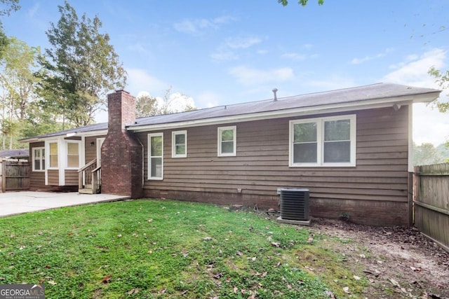 rear view of house featuring fence, a chimney, a lawn, and a patio area