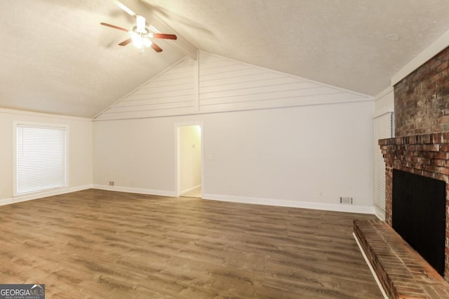 unfurnished living room featuring a ceiling fan, a fireplace, wood finished floors, baseboards, and lofted ceiling with beams