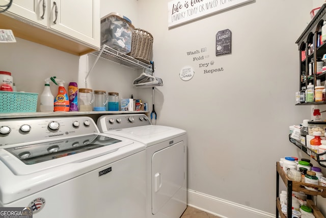 laundry area featuring cabinets, light tile patterned floors, and washing machine and clothes dryer