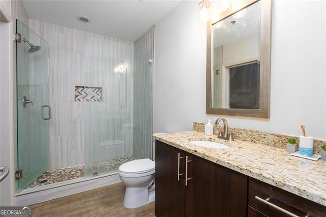 bathroom with toilet, vanity, hardwood / wood-style floors, and walk in shower