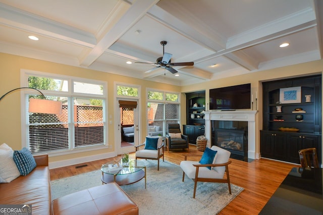 living room with coffered ceiling, beam ceiling, a healthy amount of sunlight, and light hardwood / wood-style flooring