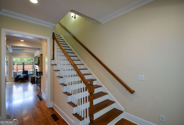 staircase with beam ceiling, crown molding, and wood-type flooring