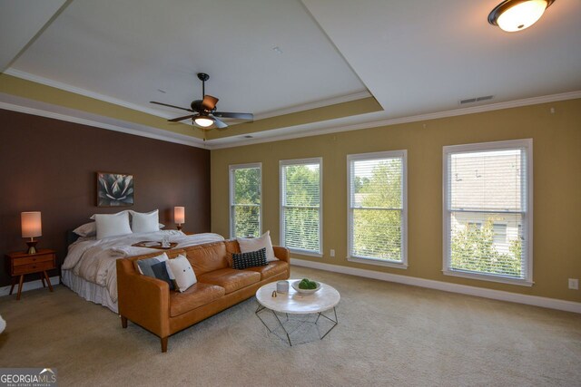 bedroom featuring light carpet, ornamental molding, a tray ceiling, and ceiling fan