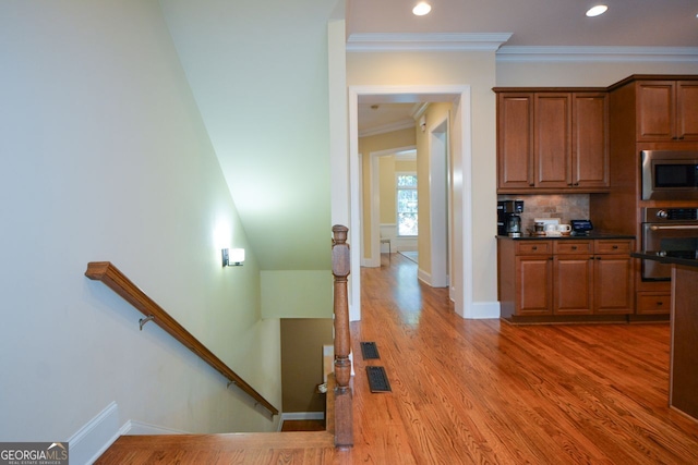 kitchen featuring crown molding, tasteful backsplash, appliances with stainless steel finishes, and hardwood / wood-style floors