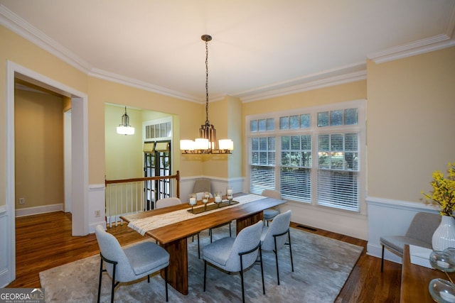 dining space with ornamental molding, a chandelier, and dark hardwood / wood-style floors