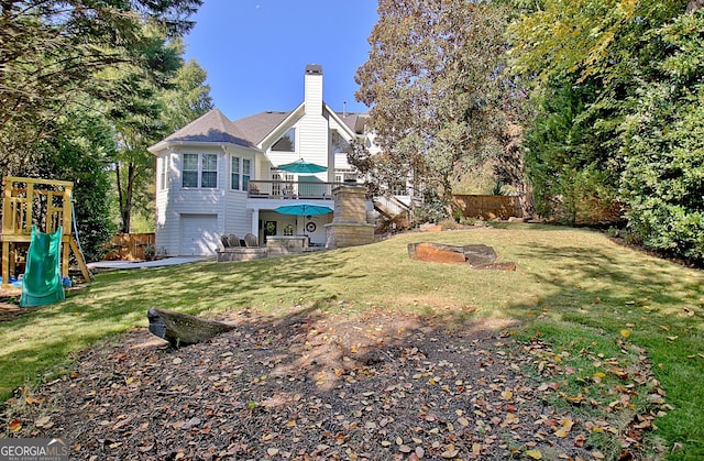 view of yard featuring a garage, a playground, and a balcony