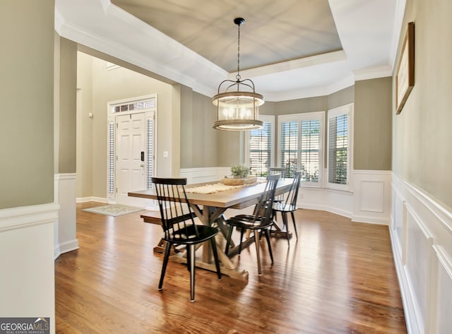 dining room with a notable chandelier, wood-type flooring, crown molding, and a tray ceiling