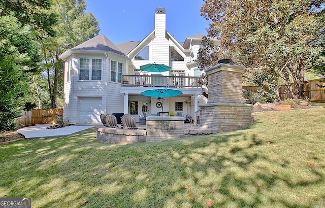 rear view of property featuring a lawn, a patio area, a deck, and a garage