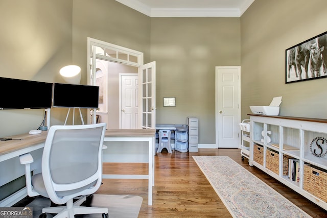 office area with hardwood / wood-style floors, ornamental molding, and a high ceiling