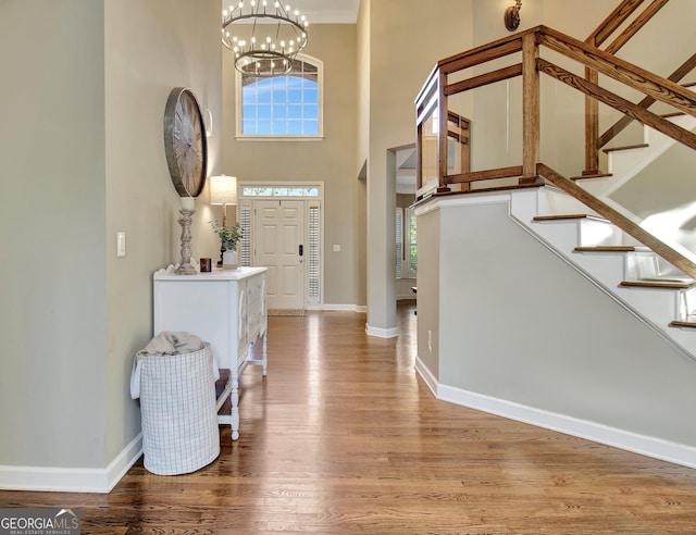 foyer featuring a towering ceiling, a chandelier, and hardwood / wood-style flooring