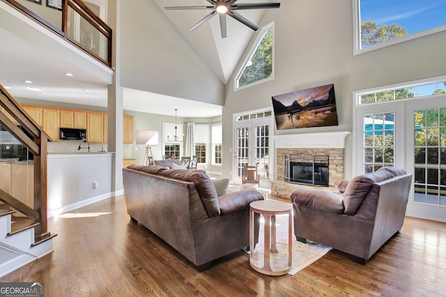 living room featuring ceiling fan, french doors, high vaulted ceiling, dark hardwood / wood-style floors, and a fireplace