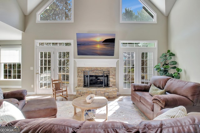 living room featuring high vaulted ceiling, a stone fireplace, and a wealth of natural light