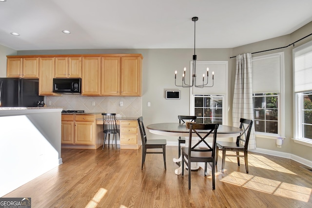 dining space with light hardwood / wood-style floors and a notable chandelier