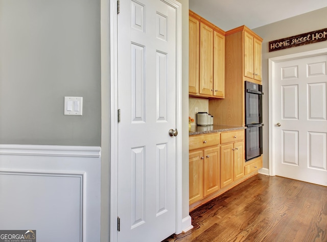 kitchen with backsplash, black double oven, dark hardwood / wood-style floors, and light brown cabinets