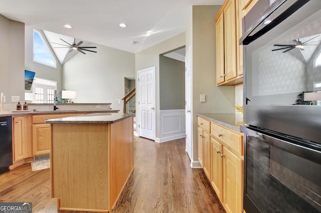 kitchen featuring light brown cabinets, a center island, light hardwood / wood-style flooring, and black appliances