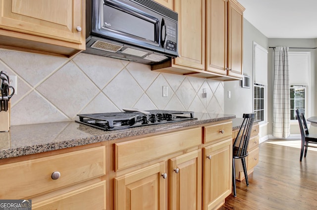 kitchen with decorative backsplash, light brown cabinets, light wood-type flooring, and gas stovetop